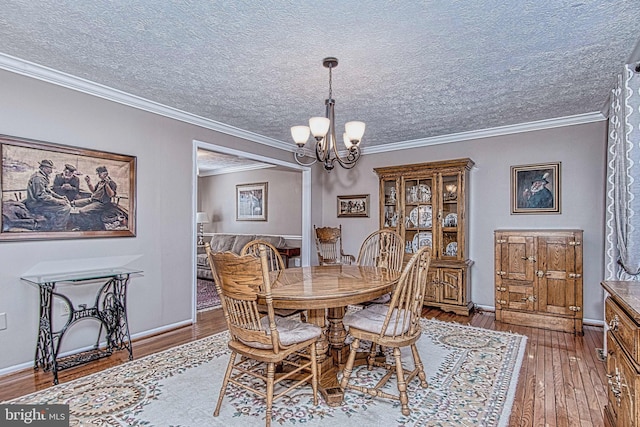 dining area featuring ornamental molding, hardwood / wood-style floors, a textured ceiling, and a notable chandelier