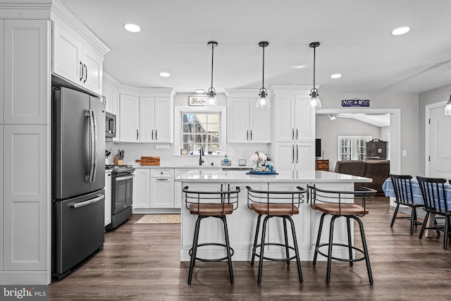 kitchen featuring appliances with stainless steel finishes, a breakfast bar area, a center island, and white cabinets