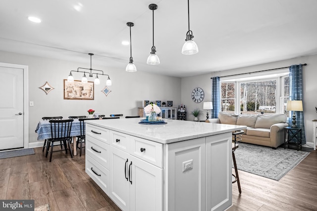 kitchen featuring baseboards, dark wood-type flooring, a center island, white cabinetry, and pendant lighting