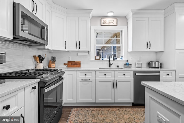 kitchen featuring stainless steel appliances, a sink, white cabinetry, and decorative backsplash