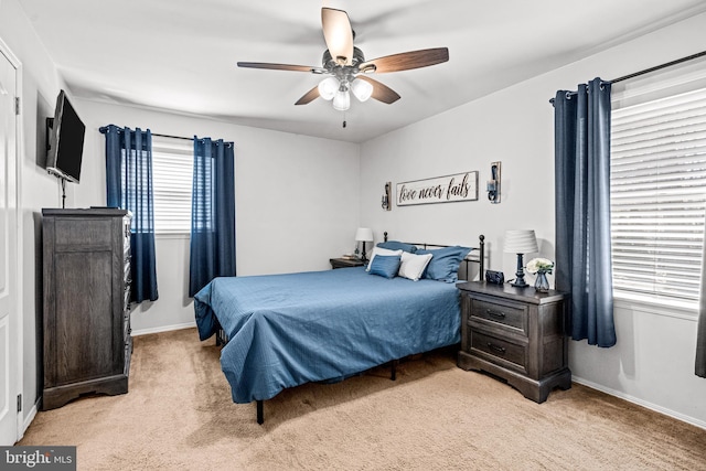 bedroom with light carpet, baseboards, and a ceiling fan