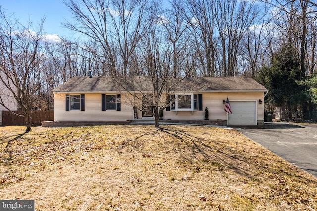 ranch-style house featuring an attached garage, driveway, and fence