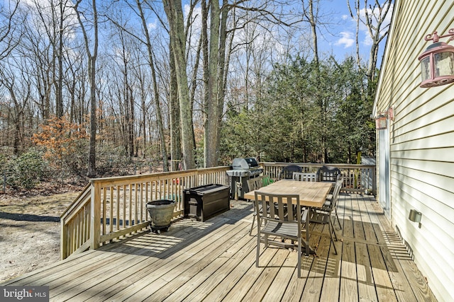 wooden deck featuring a grill and outdoor dining space