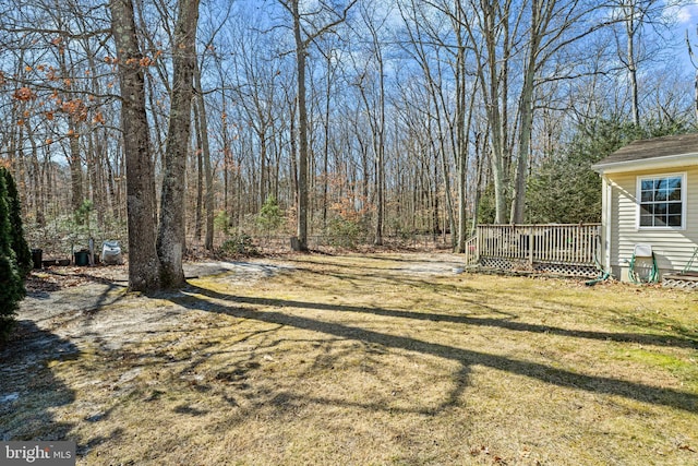 view of yard with a deck and a wooded view