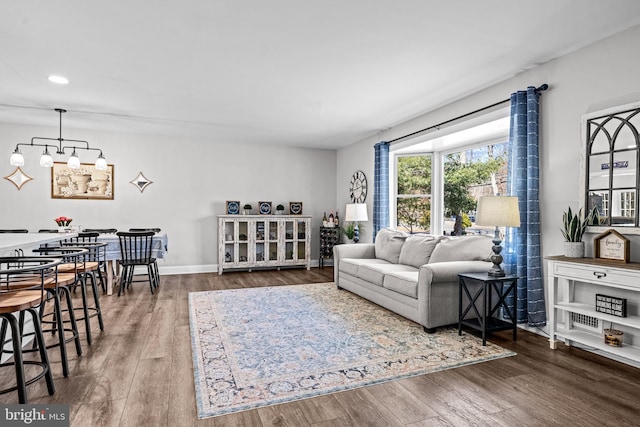 living area with a notable chandelier, baseboards, wood finished floors, and recessed lighting