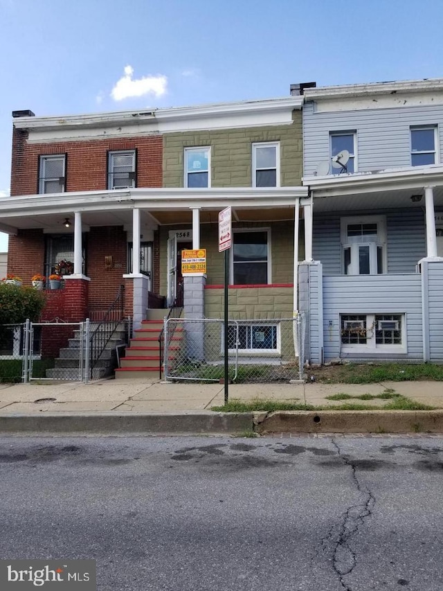 townhome / multi-family property with a porch and brick siding