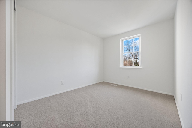 spare room with carpet, visible vents, and baseboards