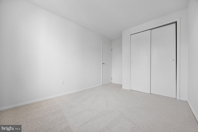 unfurnished bedroom with carpet, baseboards, and a closet