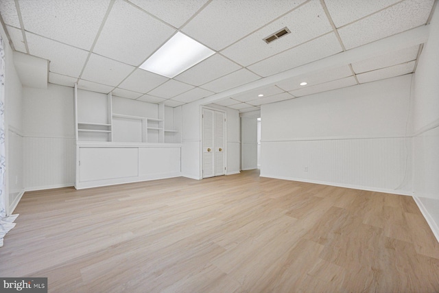 unfurnished room featuring a paneled ceiling, a wainscoted wall, visible vents, and wood finished floors