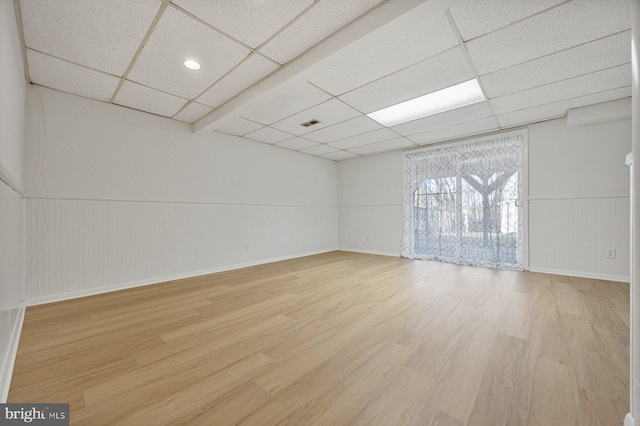 spare room featuring a paneled ceiling, wainscoting, visible vents, and light wood finished floors