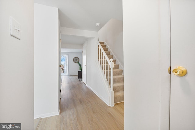 interior space featuring stairs, light wood-type flooring, and baseboards