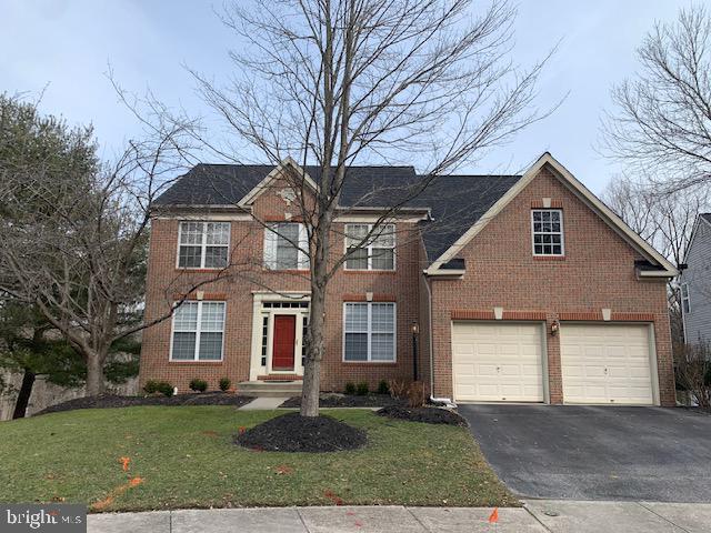 colonial inspired home with aphalt driveway, a front yard, brick siding, and a garage