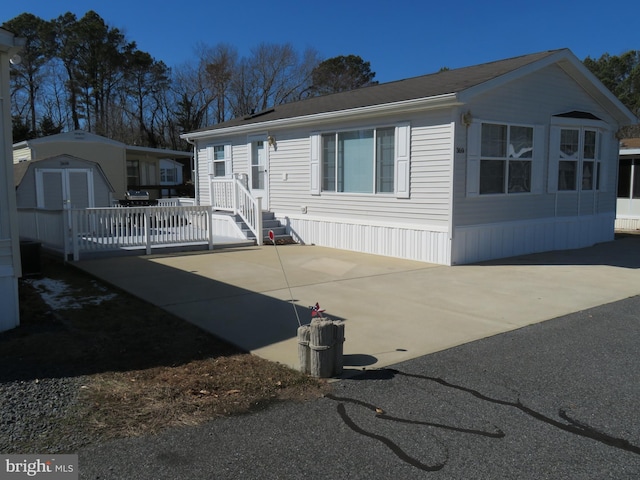 manufactured / mobile home with an outbuilding, concrete driveway, and a storage unit