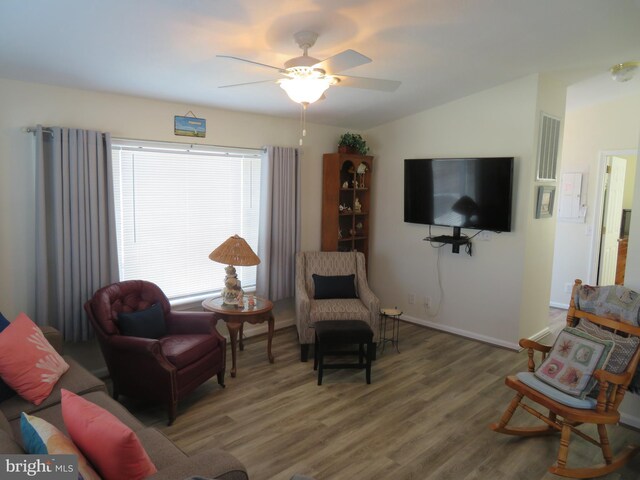 living area with a ceiling fan, lofted ceiling, baseboards, and wood finished floors