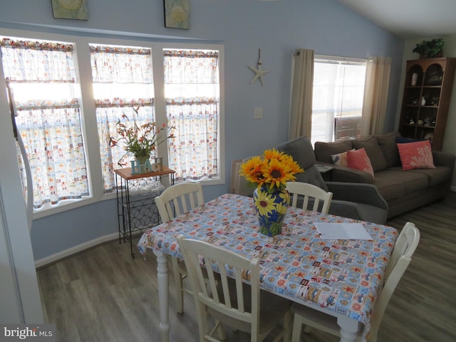 dining area featuring vaulted ceiling, baseboards, and wood finished floors