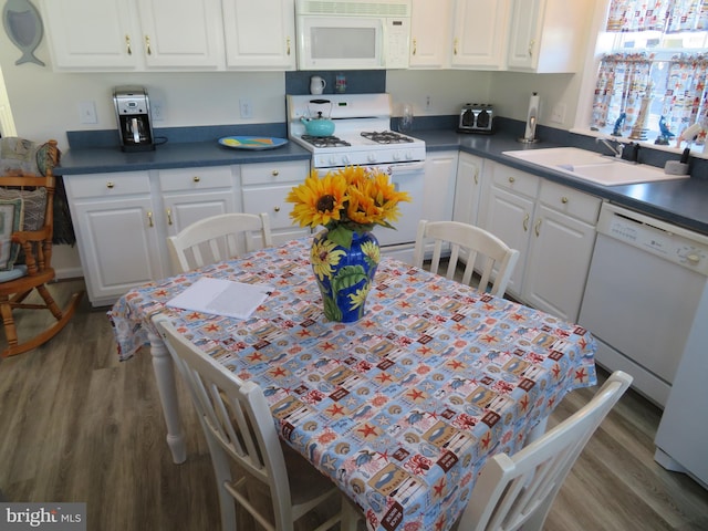 kitchen with white appliances, white cabinetry, a sink, and wood finished floors