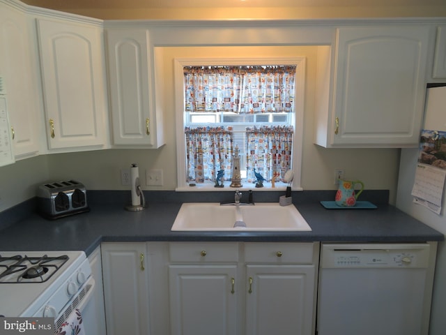 kitchen featuring dishwasher, dark countertops, a sink, and white cabinetry