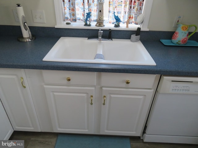 kitchen with dark countertops, white dishwasher, and white cabinets