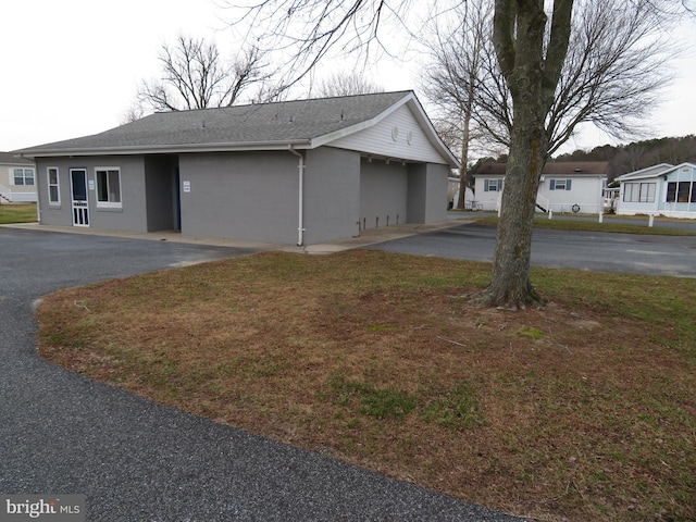 ranch-style house featuring a front yard and roof with shingles