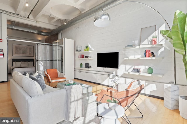 living area with light wood finished floors and brick wall