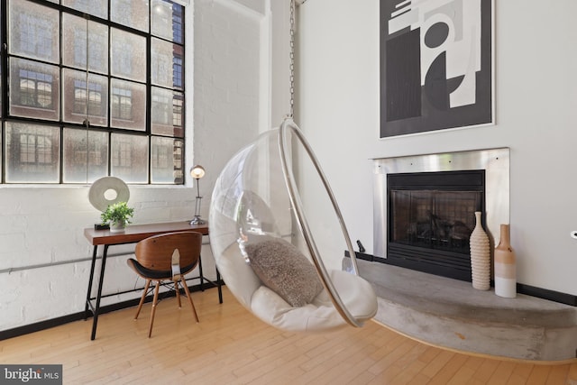 living area featuring wood-type flooring and a glass covered fireplace