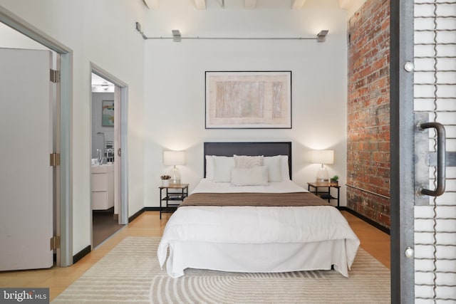 bedroom featuring brick wall, baseboards, and wood finished floors