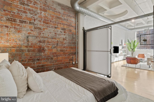 bedroom featuring coffered ceiling, beamed ceiling, brick wall, and wood finished floors