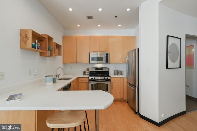 kitchen with stainless steel appliances, a peninsula, a sink, light countertops, and open shelves