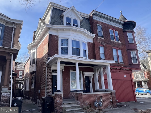 view of front facade featuring a porch, mansard roof, and brick siding