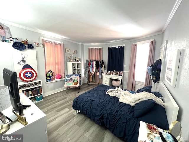 bedroom featuring baseboards, ornamental molding, and wood finished floors