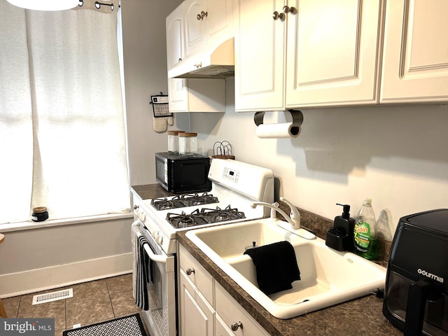 kitchen featuring under cabinet range hood, visible vents, tile patterned floors, gas range gas stove, and dark countertops