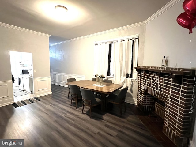 dining space featuring crown molding, a fireplace, a decorative wall, wainscoting, and wood finished floors