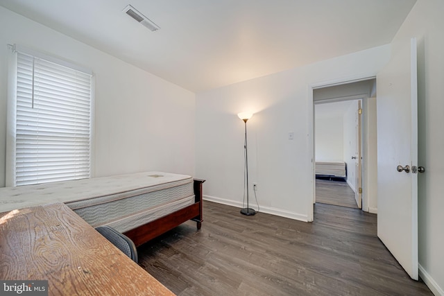 bedroom featuring baseboards, visible vents, and wood finished floors