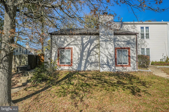 rear view of property featuring a yard, a chimney, and fence