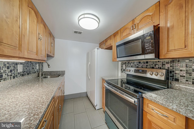 kitchen featuring stainless steel appliances, a sink, visible vents, baseboards, and tasteful backsplash