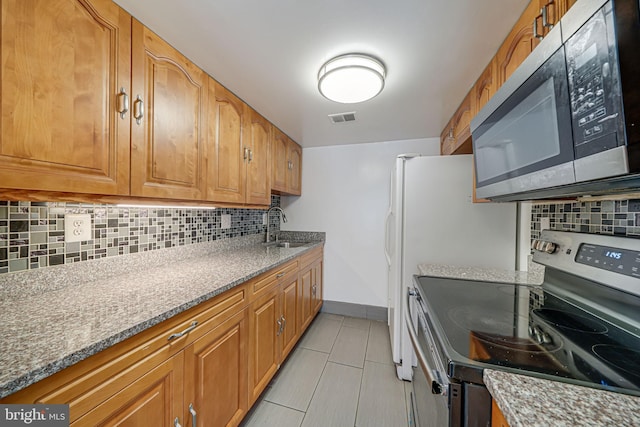 kitchen with stone countertops, visible vents, appliances with stainless steel finishes, a sink, and backsplash