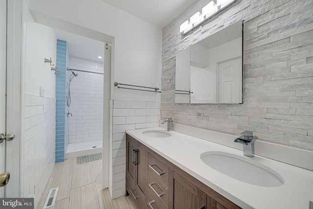 bathroom with tile walls, visible vents, a sink, and a stall shower