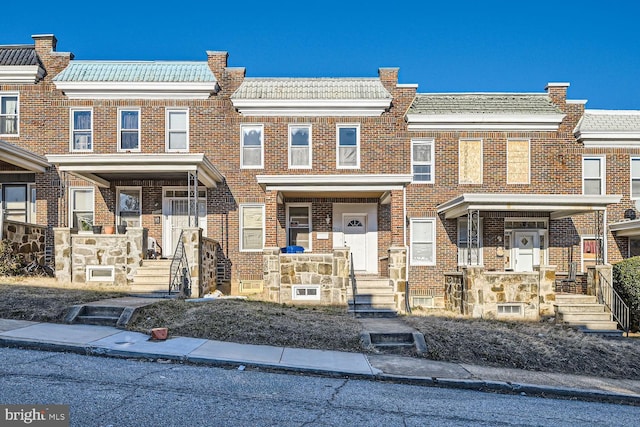 view of property featuring brick siding and a tile roof