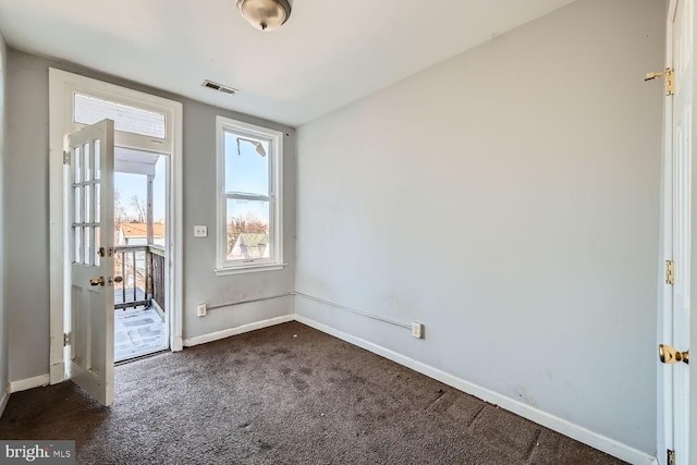 spare room featuring baseboards, visible vents, and dark carpet