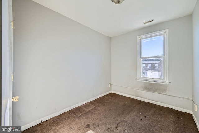 spare room with baseboards, visible vents, and dark carpet