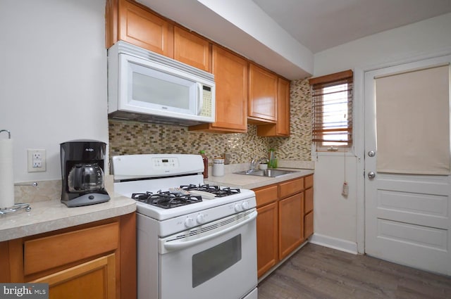 kitchen with white appliances, dark wood finished floors, light countertops, and a sink