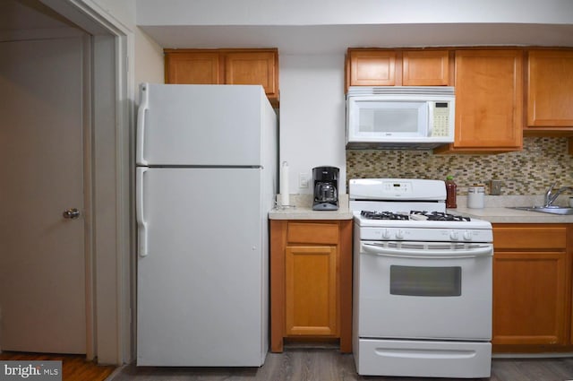 kitchen featuring tasteful backsplash, white appliances, light countertops, and wood finished floors