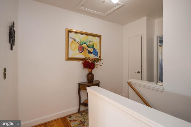 hallway with attic access, baseboards, and wood finished floors