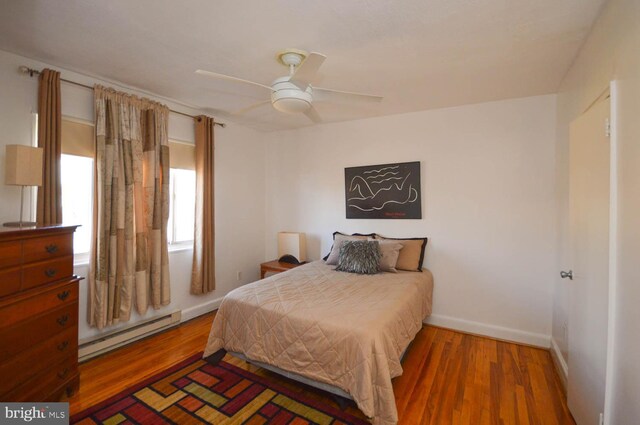 bedroom with a baseboard radiator, wood finished floors, and baseboards