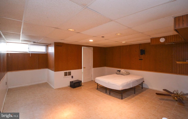 unfurnished room with wood walls, visible vents, and a drop ceiling