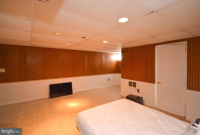 bedroom featuring wooden walls, visible vents, a drop ceiling, and recessed lighting