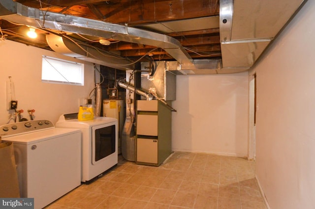 clothes washing area featuring laundry area, water heater, and washer and clothes dryer