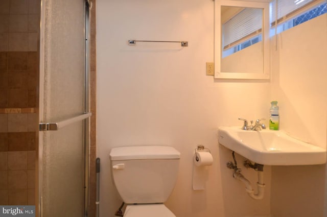 bathroom with a stall shower, a sink, and toilet