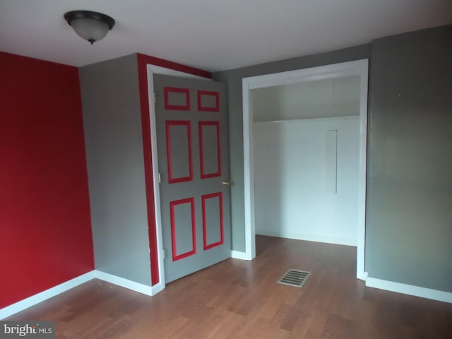 empty room featuring baseboards, visible vents, and wood finished floors