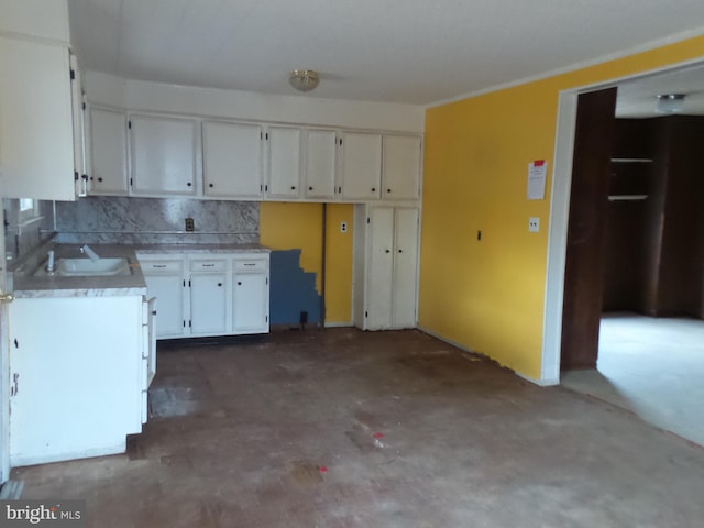 kitchen with light countertops, white cabinetry, a sink, and unfinished concrete floors